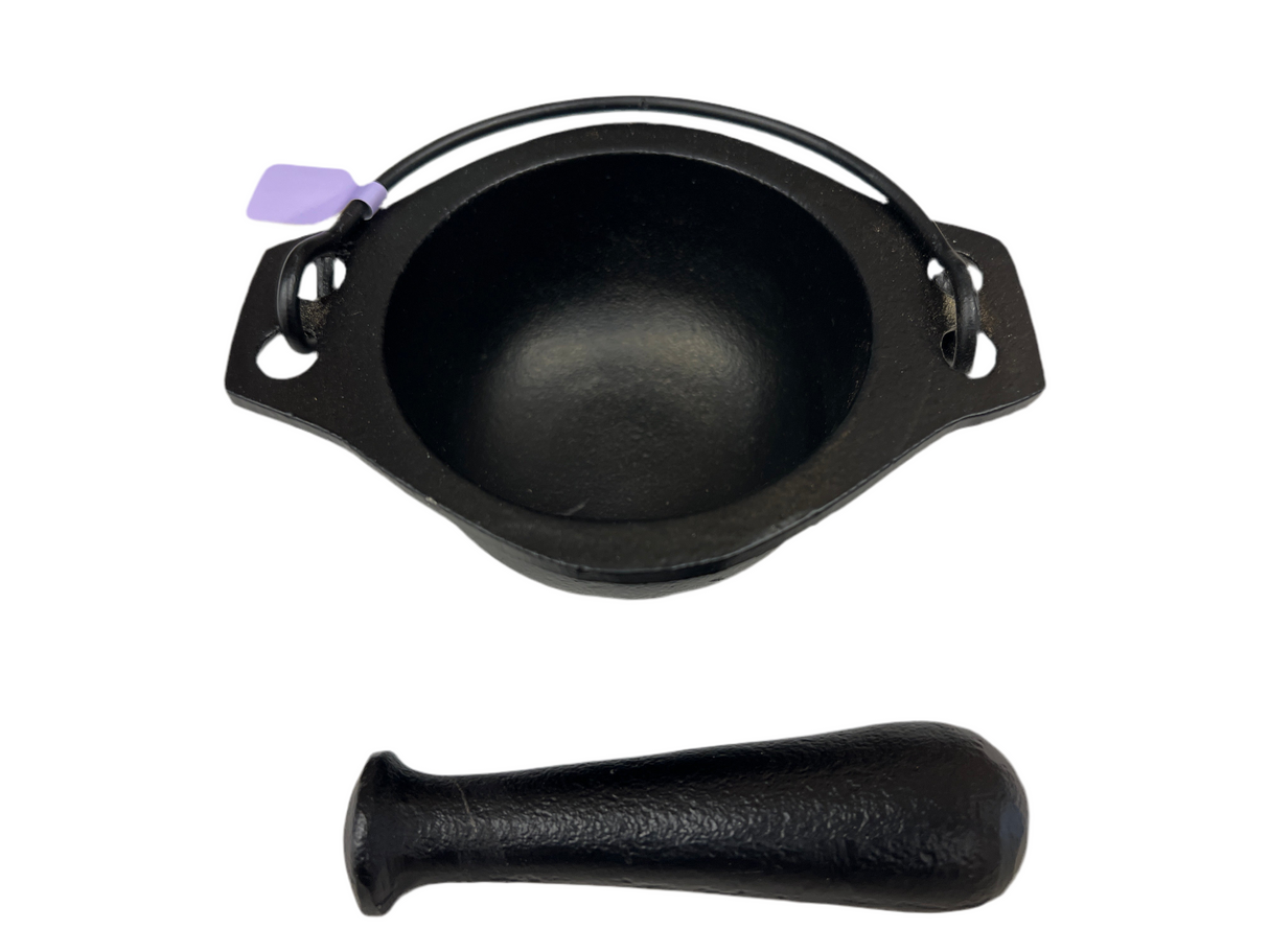 black cast iron cauldron with with metal pestle