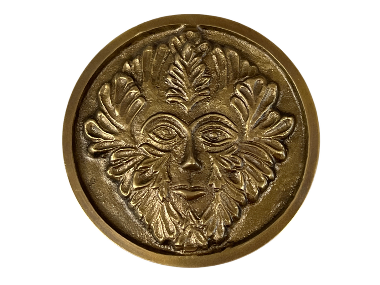 Golden colored disk with a image of the green man in relief
