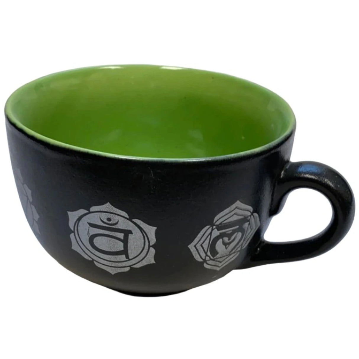 Black ceramic mug with a green interior and seven white chakra symbols.