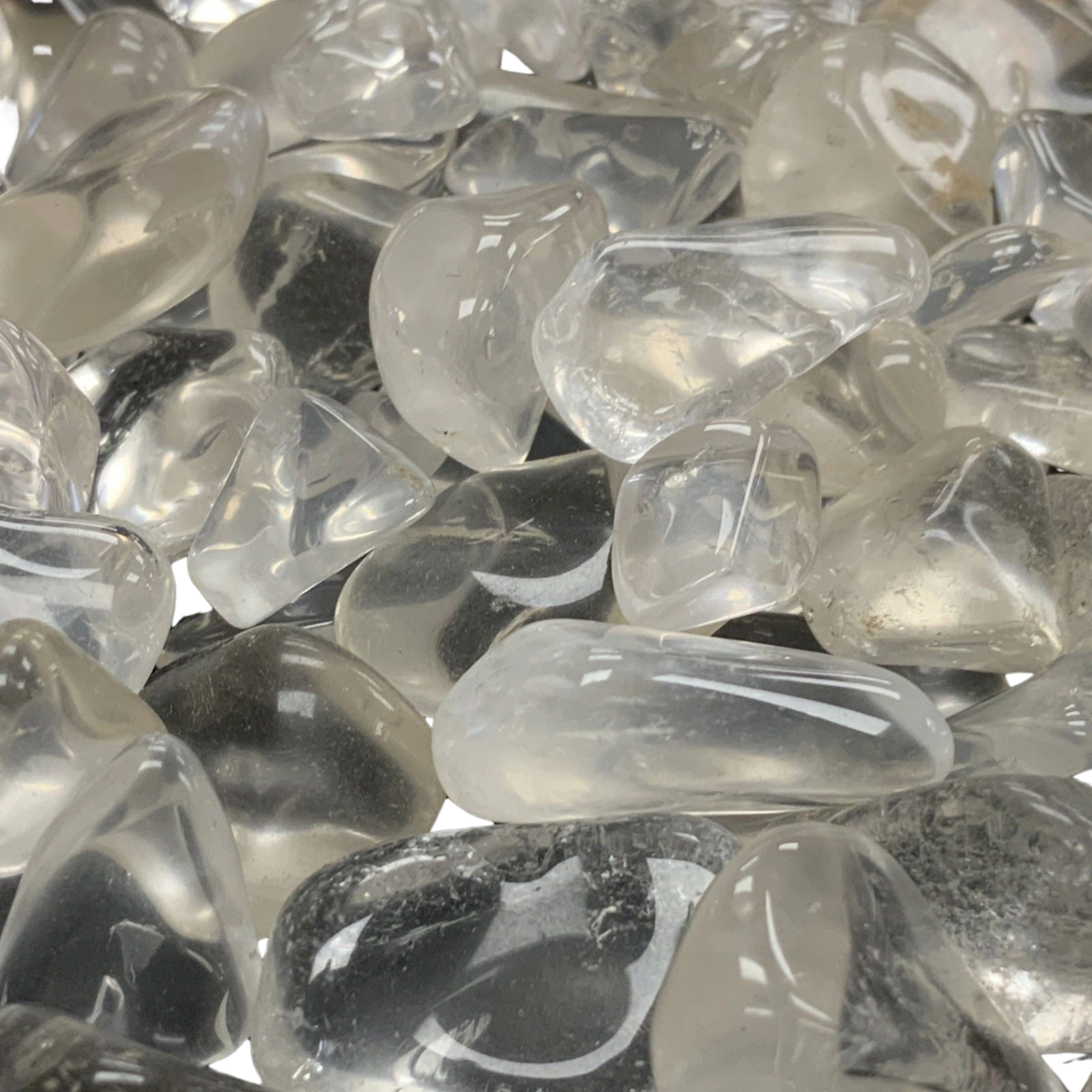A cluster of small, tumbled clear quartz stones with a smooth, polished finish.