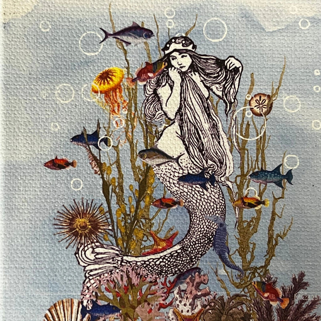 Mermaid canvas magnet with illustration of a mermaid surrounded by sea creatures and coral reef.