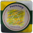 Yellow and black square candle with "POSITIVE ENERGY" label and atom symbol.