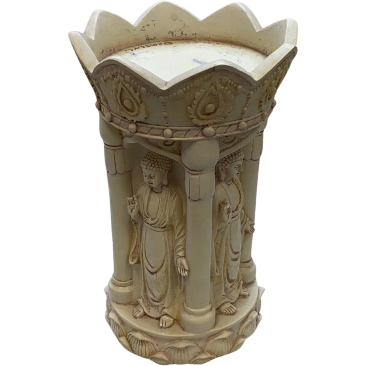White ceramic candle holder with three standing Buddha figures surrounding a central bowl. The top of the holder has a scalloped design.