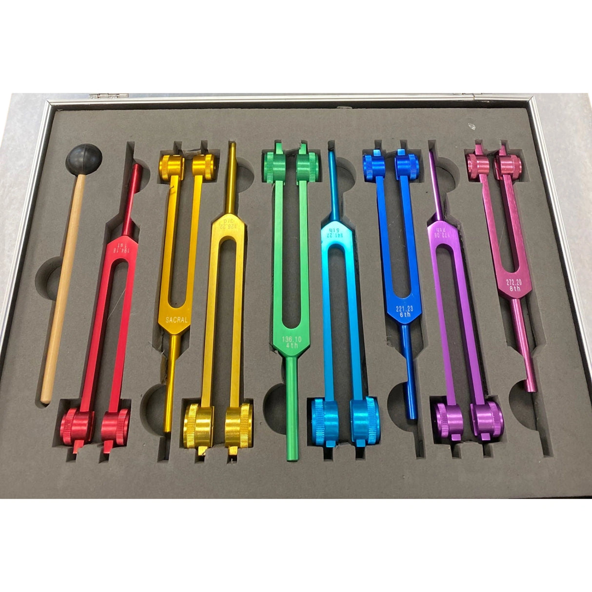 Tuning fork set with eight colored tuning forks and a mallet in a gray case.