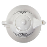White ceramic teapot with a matching saucer, featuring black gothic-style witch illustrations and the word 'WITCH' printed on the lid.