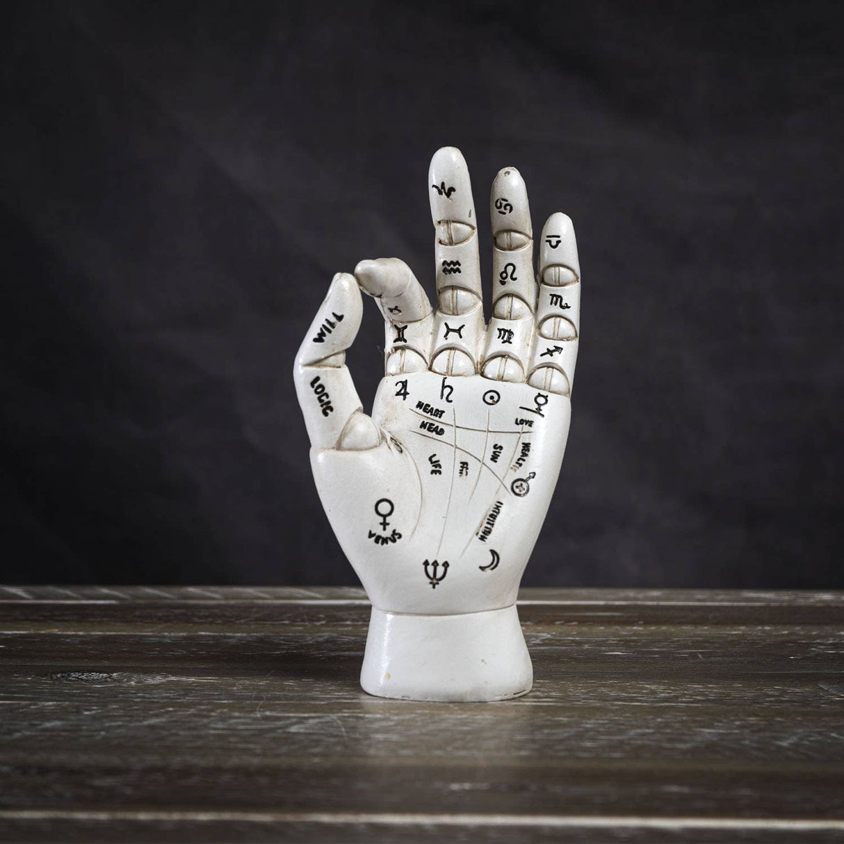 Decorative palmistry hand sculpture on a wooden surface with a dark background