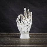 Decorative palmistry hand sculpture on a wooden surface with a dark background