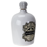 A white ceramic bottle with a ribbed gray stopper and a vintage-style black label reading 'Wink's Weirdity's Nevermore! Dr. Fun's Alchemy Raven's Cure'.