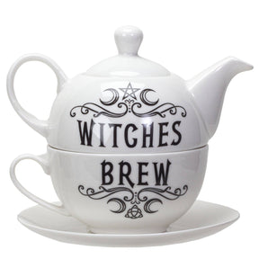 White ceramic teapot and matching teacup with saucer, featuring black gothic-style text reading 'WITCHES BREW' with decorative swirls and a pentagram symbol.