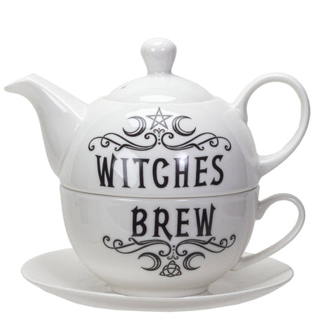 A white ceramic teapot and matching teacup with saucer set, featuring black gothic-style text reading 'WITCHES BREW' with decorative swirls, a pentagram, and crescent moon motif.