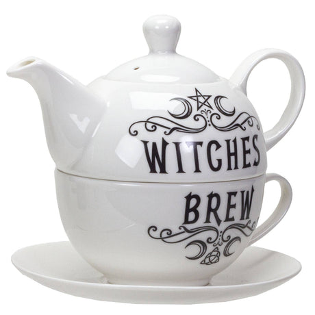 A white ceramic teapot and matching cup set with a saucer, featuring black gothic-style text reading 'WITCHES BREW' and decorative swirls and a star motif.