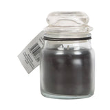 Black candle in a clear glass jar with a label on a white background