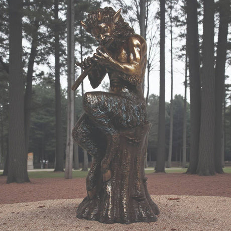 Bronze statue of a satyr playing a flute in a forest setting