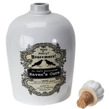 A white ceramic bottle labeled 'Raven's Cure' with a vintage-style black label featuring ravens and gothic text, shown alongside a small detached white stopper with a cork on a white background.