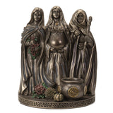 Bronze figurine of three hooded figures with a cauldron and flowers on a white background