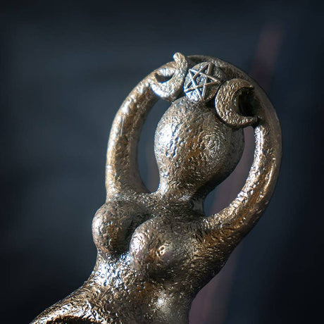 Metallic figurine with a star and crescent moon design on a dark background