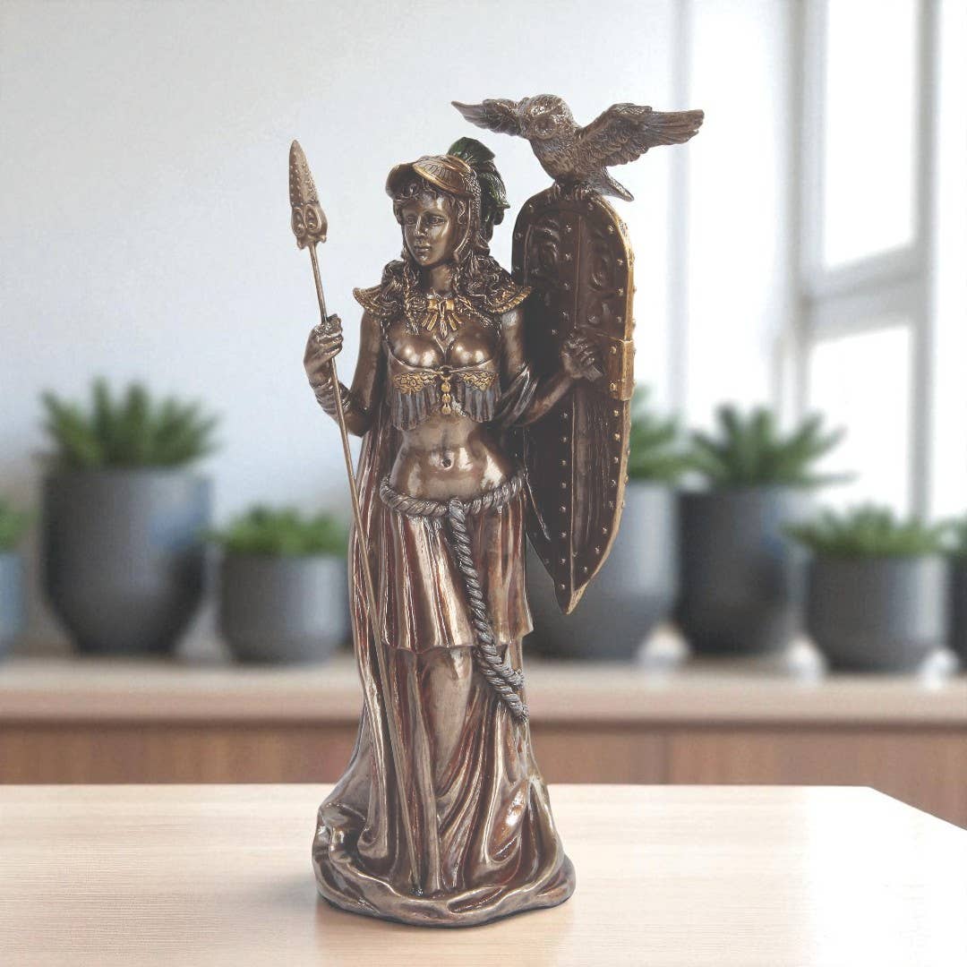 Bronze statue of a warrior with a shield and spear on a table with plants in the background
