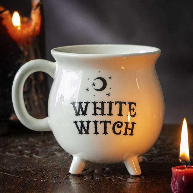 White mug with 'White Witch' text on a dark background with candles