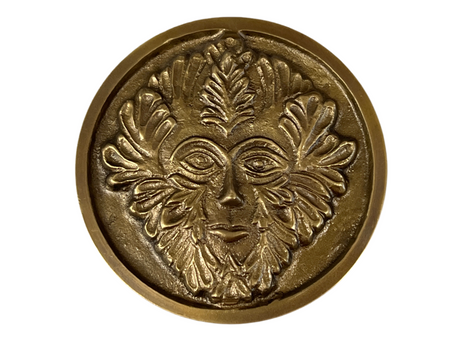 Golden colored disk with a image of the green man in relief 
