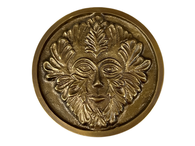 Golden colored disk with a image of the green man in relief 