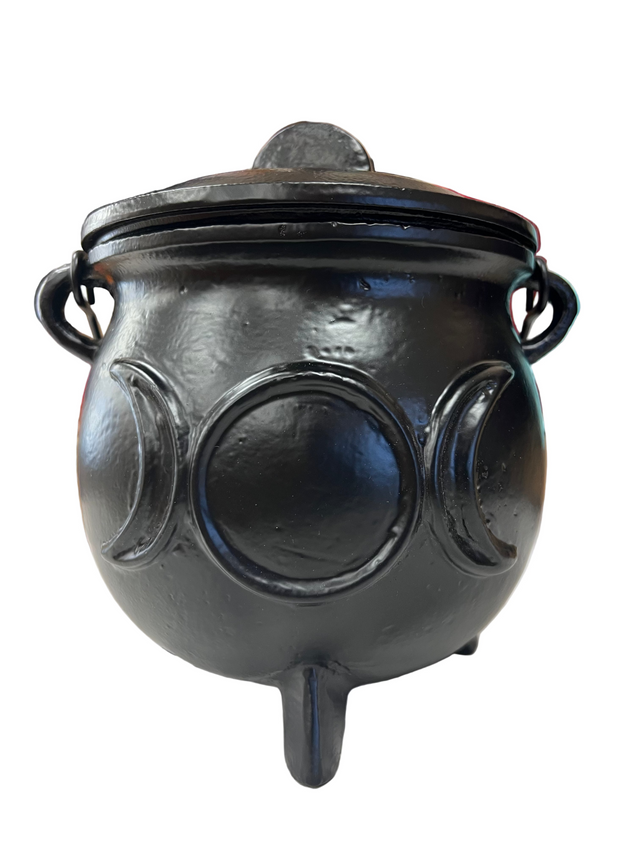 Black cauldron on a white surface with a blurred background of jewelry.