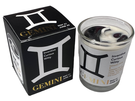 Candle with Gemini zodiac design next to its packaging on a light gray background