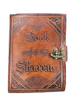 Leather-bound book titled 'Book of Shadows' with embossed text and a latch on a white background.