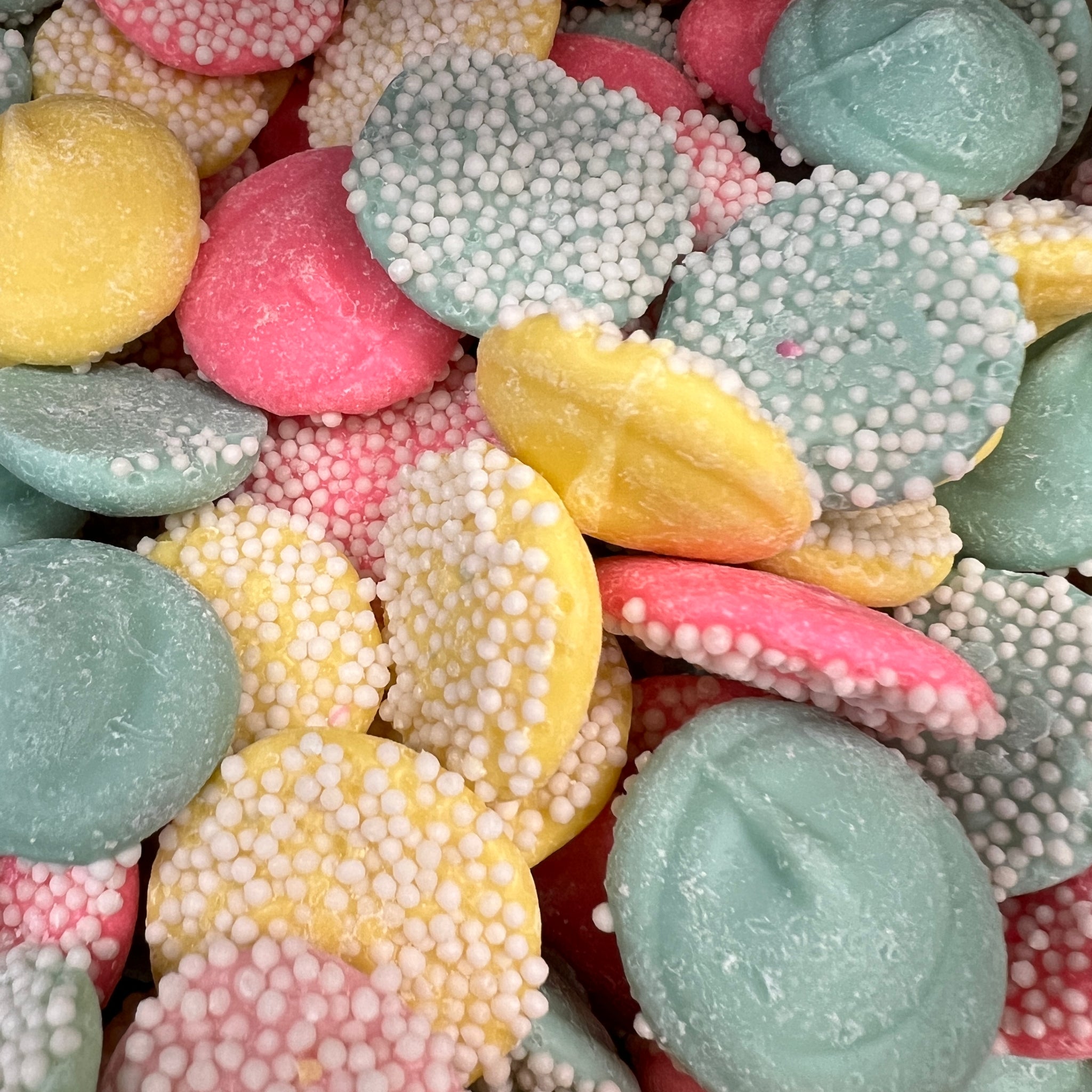 Round quarter size multi colored pastel candy with white sprinkle topping 