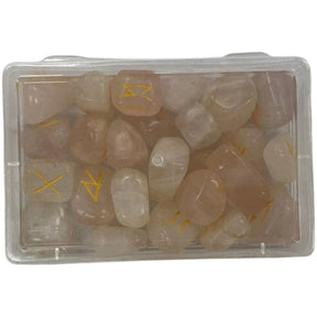 Pink rose quartz stones with gold runes engraved on them in a clear plastic box.