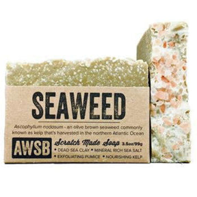 Brown bar soap with a textured surface and a label that reads "Seaweed," "Scratch Made Soap," and "AWSB." The label also includes information about the ingredients and their benefits.