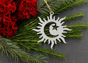 Sun, moon, and star metal ornament with greenery and red flowers.
