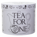 A round white tin canister with a matching lid, featuring black line art of a teapot, a teacup, a skeleton hand holding a teacup, and the words 'TEA FOR ONE' on the front.
