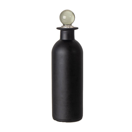 A matte black bottle with a spherical pale green glass stopper on a white background.