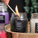 Candle being lit with a label 'Magic Spell Candle Protection Black Opium' on a wooden tray.