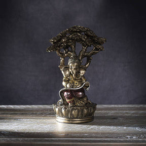 Decorative statue of a seated figure under a tree on a wooden surface with a dark background