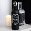 Black bottle labeled 'Deadly Poison' with a candle in the background