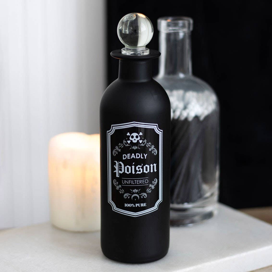 Black bottle labeled 'Deadly Poison' with a candle in the background
