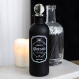 Black bottle labeled 'Deadly Poison' with a candle in the background