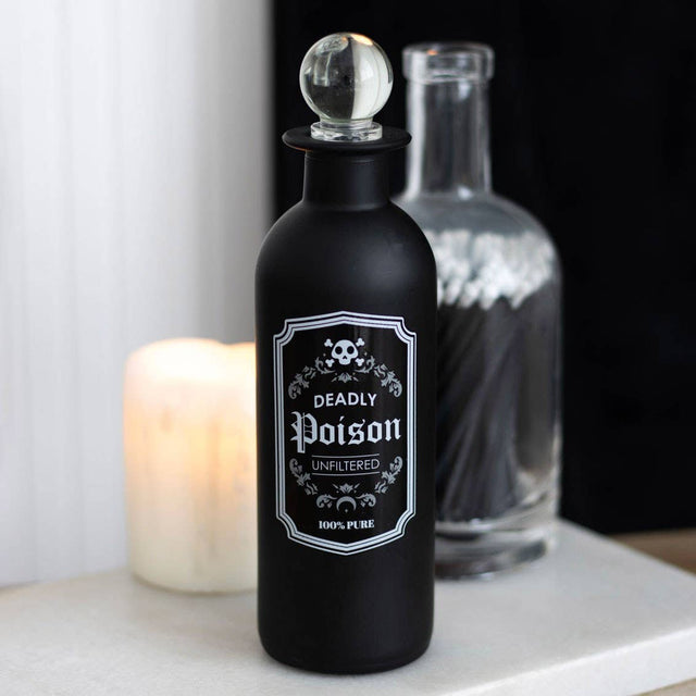 Black bottle labeled 'Deadly Poison' with a candle in the background
