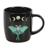 Black mug with a green moth and moon phases design on a white background