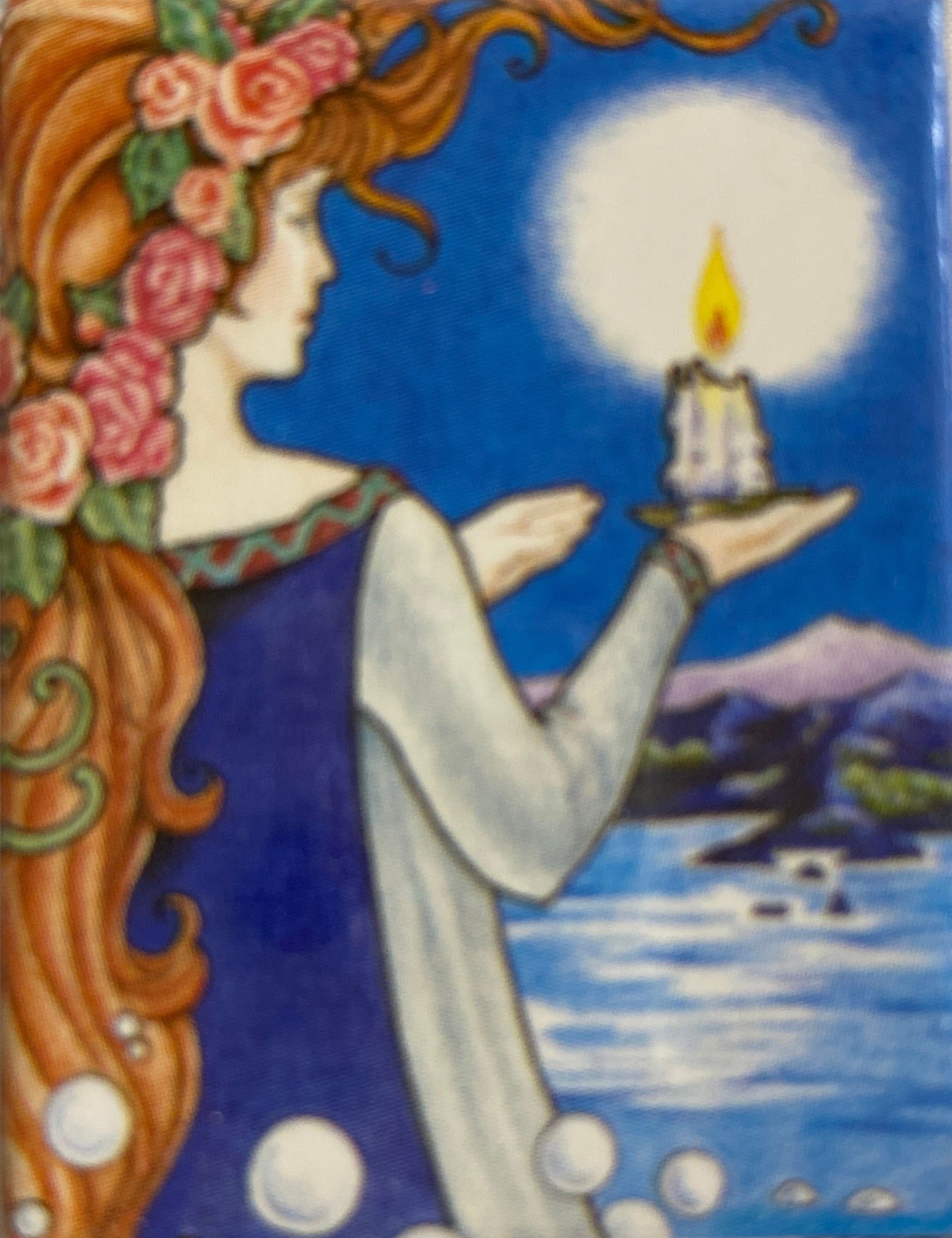 back of deck shows woman holding a candle overlooking ocean 